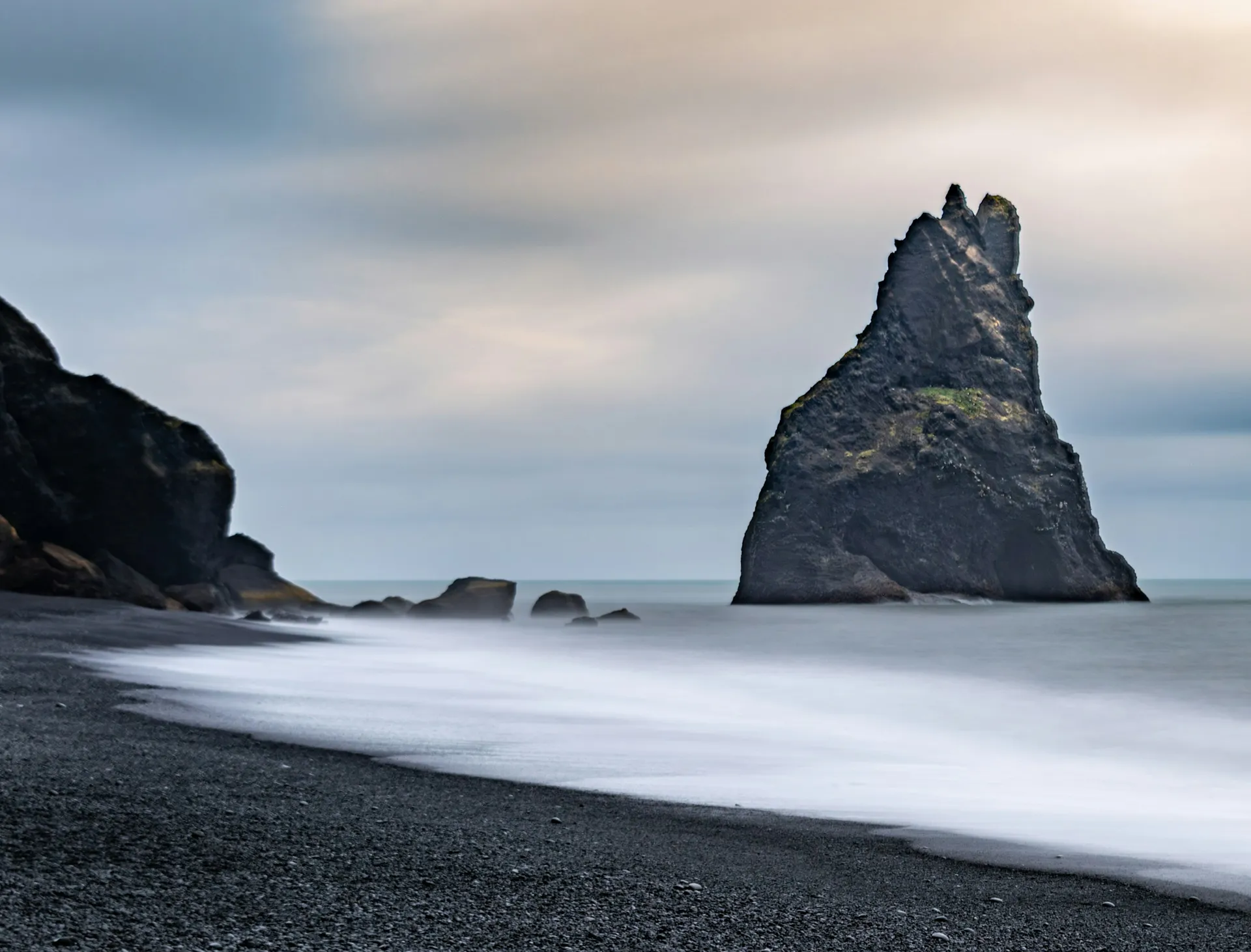 Plage de sable noir islandaise sous une lumière dorée froide